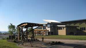 A modern building with a large glass facade and a covered outdoor area with a bicycle sculpture.