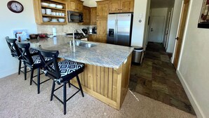 A kitchen with a central island, wooden cabinets, a stainless steel refrigerator, and a microwave.