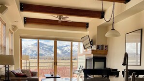 A spacious living room with a large window offering a mountain view, a fireplace, and a dining area.