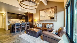 A modern kitchen with dark cabinets, a central island, and a chandelier. - Northstar Ski-in/out Condo w/ Resort Amenities! (Truckee)