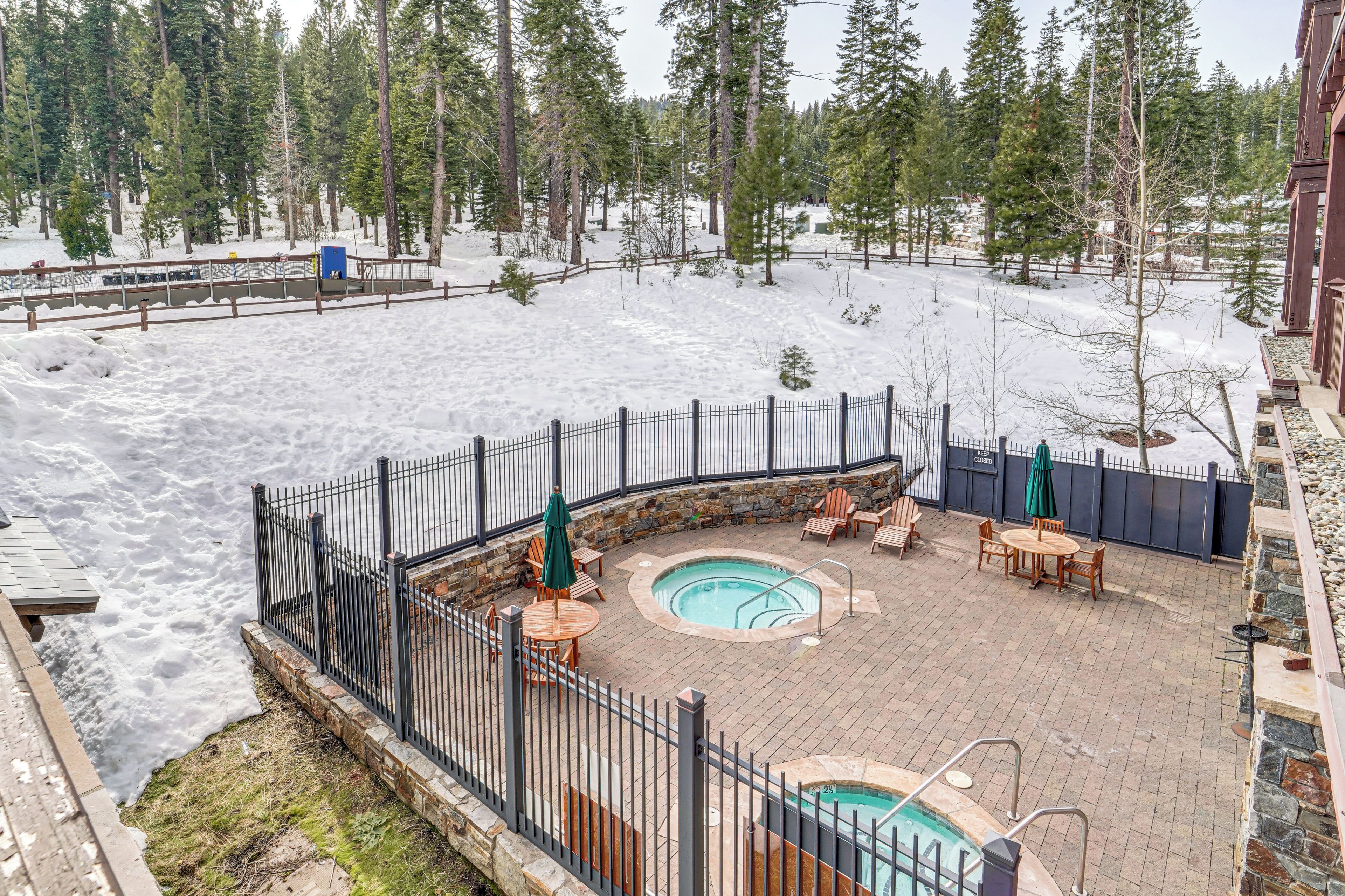 Zona exterior coberta de neu amb una piscina, mobiliari i una tanca.