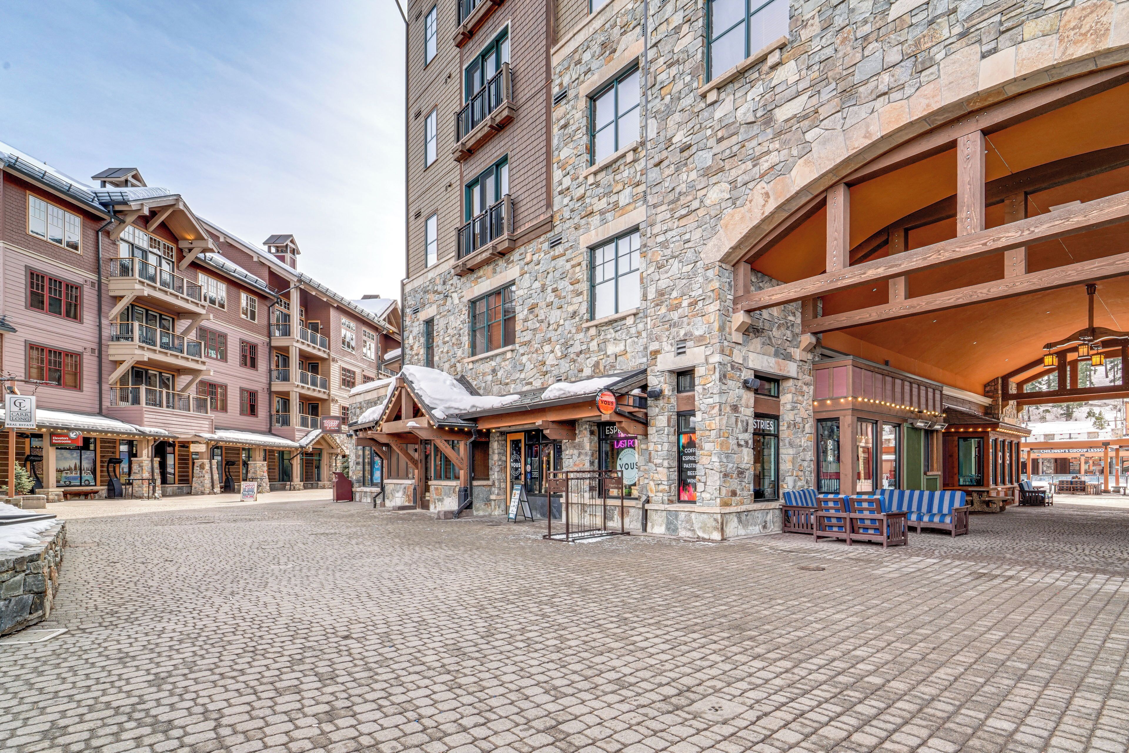 A stone building with a covered outdoor seating area and multiple windows.