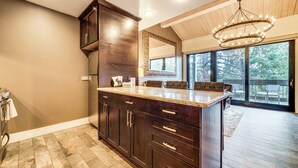 A spacious kitchen with dark wooden cabinets, a granite countertop, and a large island. - Northstar Ski-in/out Condo w/ Resort Amenities! (Truckee)