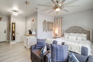 Quarto com cama, ventilador de teto, mesa de cabeceira e uma cadeira.