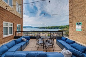 A balcony with blue seating, a table, and chairs, overlooking a lake with boats and a dock. - Smith Mtn Lake Retreat: Indoor Pool/hot Tub Access (Huddleston)