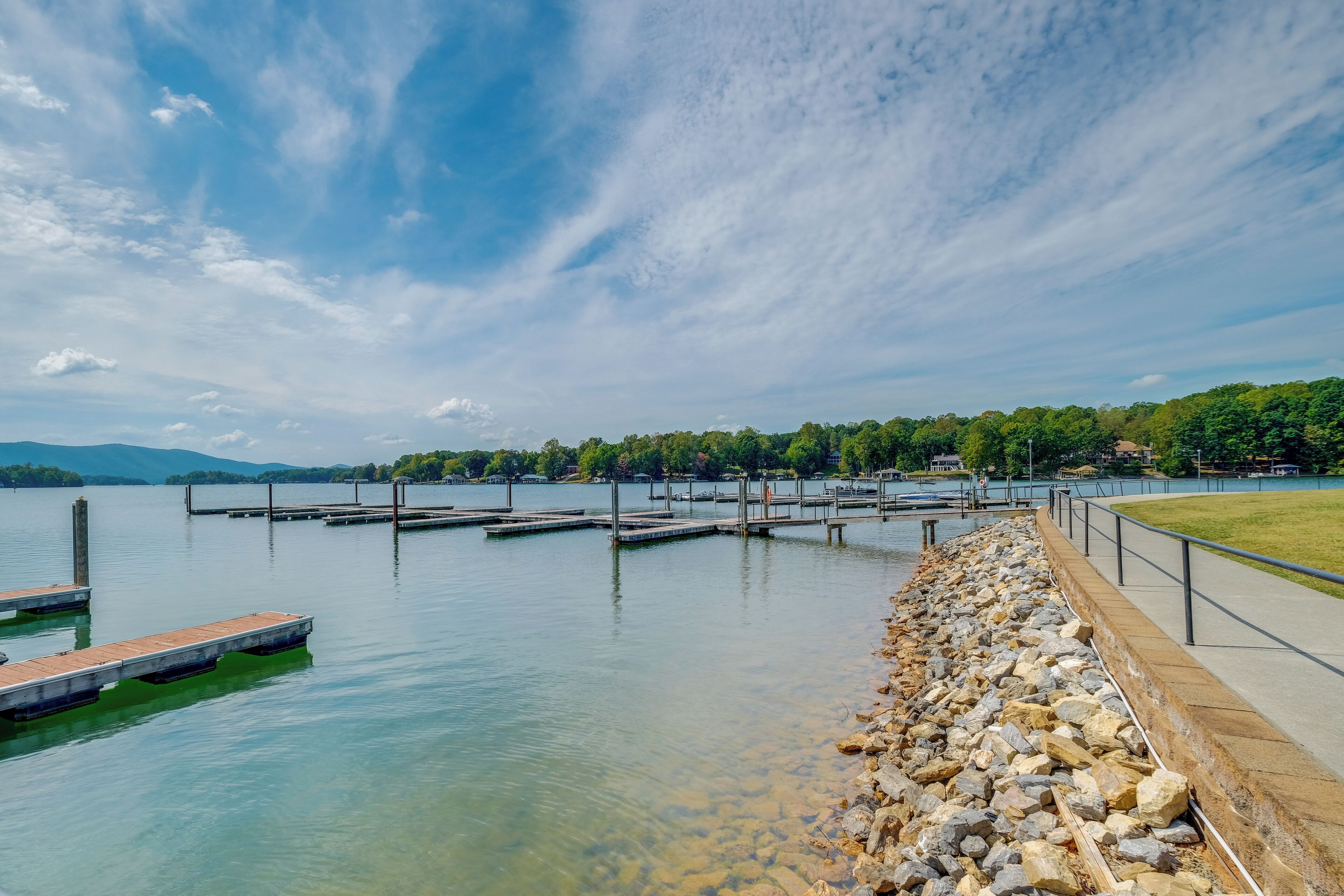 Un lac paisible, avec des quais et une promenade en pierre longeant la rive.