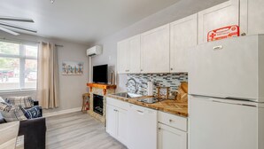 Une cuisine moderne avec des meubles blancs, un lave-vaisselle encastré, un plan de travail en bois et un réfrigérateur.