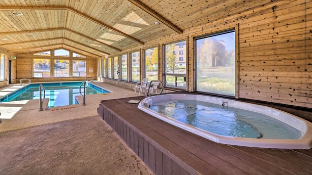 Una piscina coperta con una vasca idromassaggio, pareti in legno e ampie finestre.