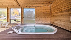 Una baita in legno con vasca idromassaggio, pareti di legno e ampie finestre.