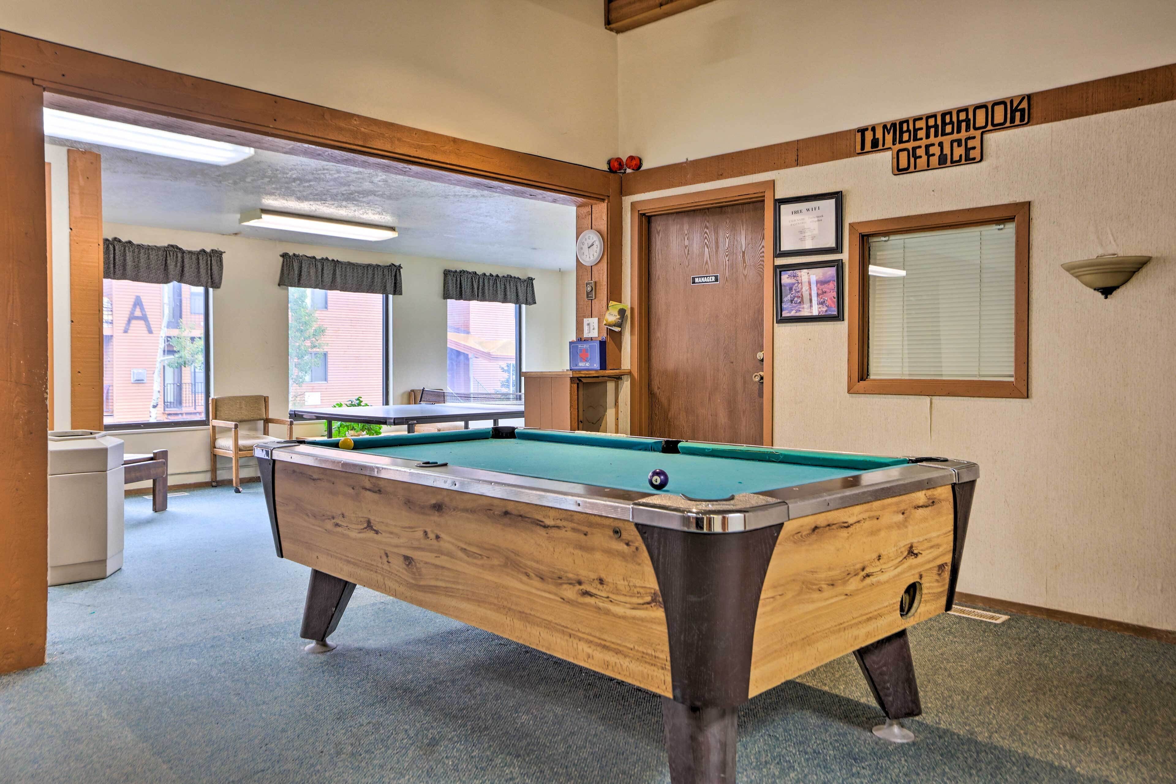 A pool table in a room with a sign reading "Timberbrook Office".