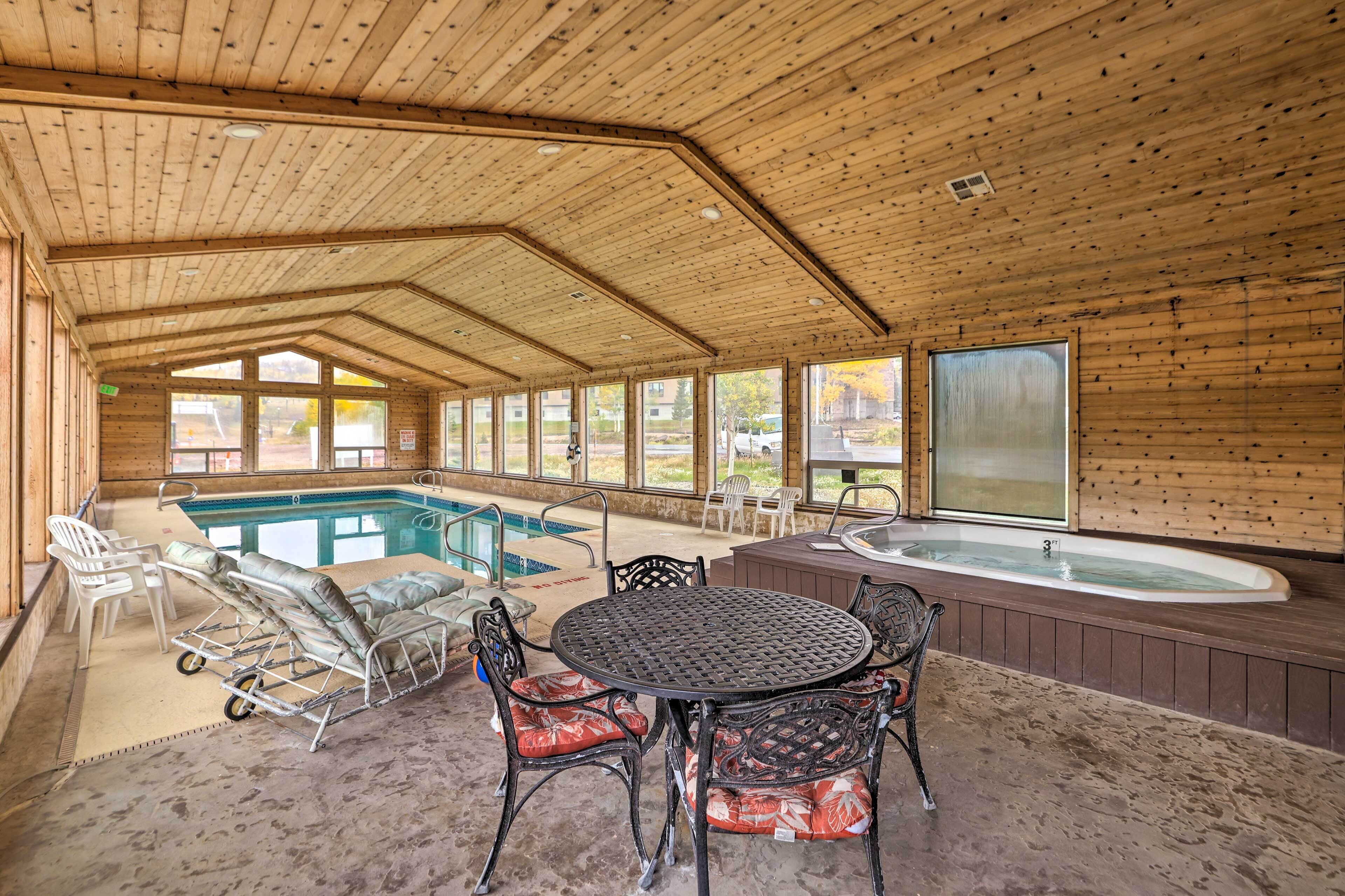 Una cabaña de madera con piscina, jacuzzi y zona de estar al aire libre.