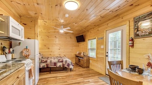 A cabin interior with a kitchen, dining area, and a bed. - Hudsons Hideaway Cabin on Creek in Beattyville! (Beattyville)