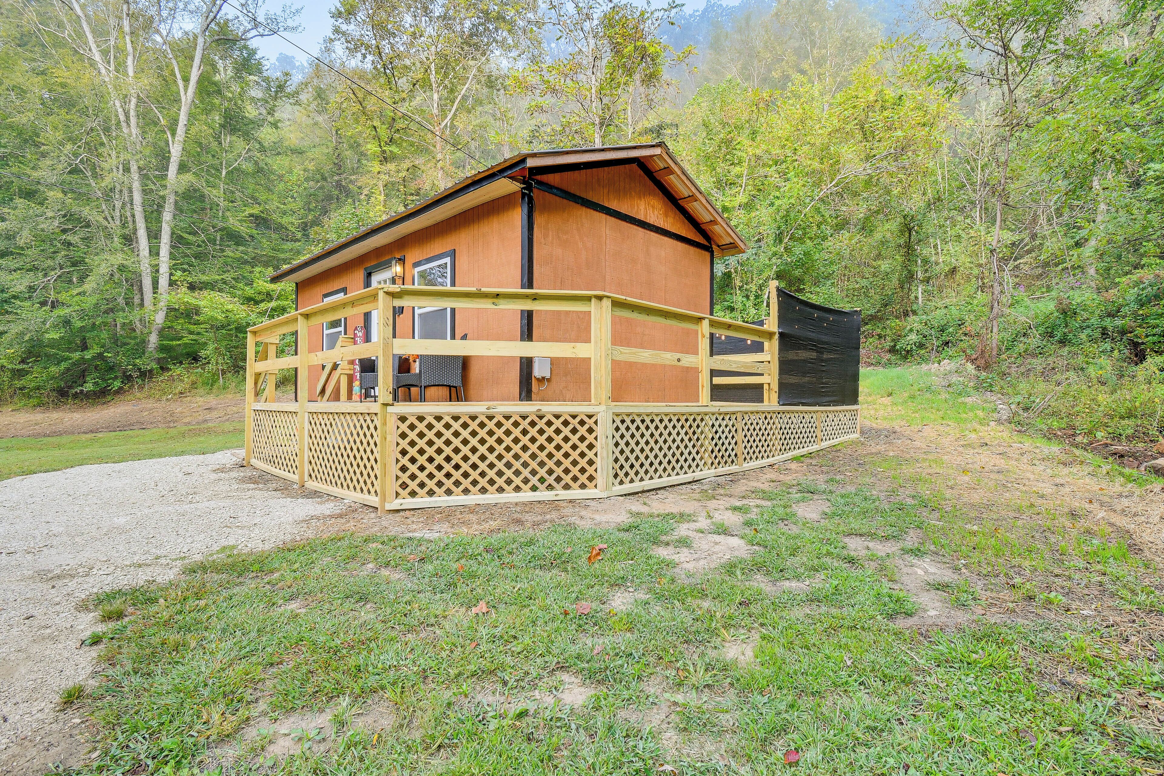 A wooden cabin with a deck, surrounded by trees.