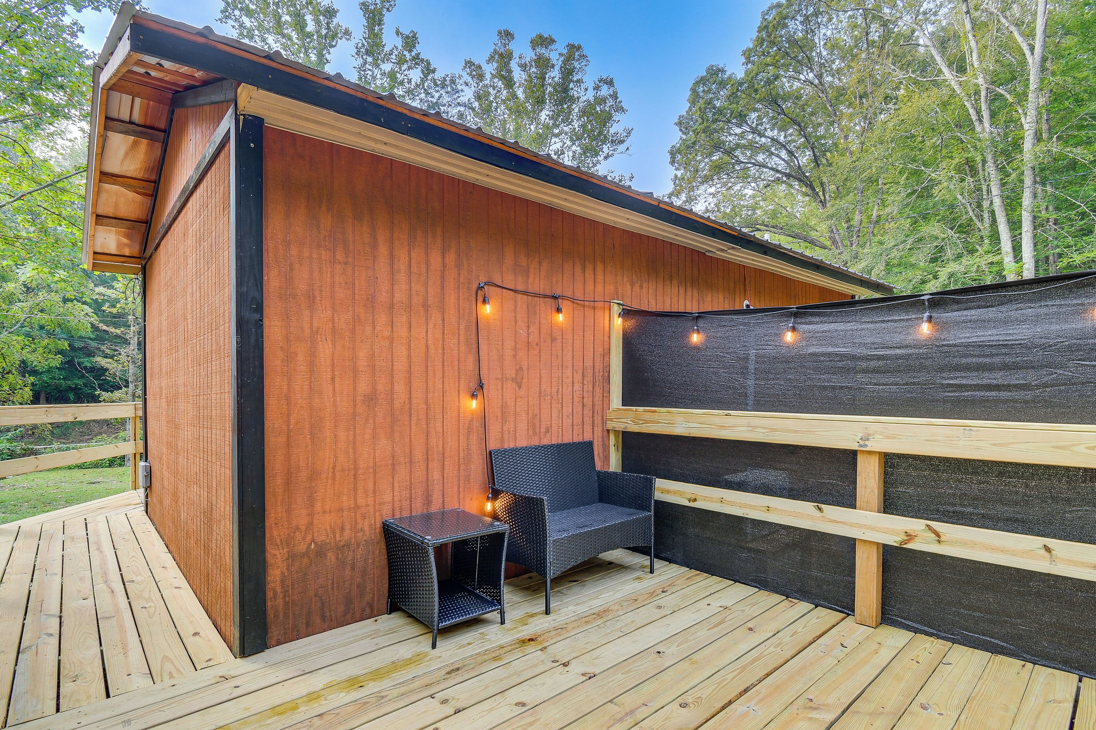 A wooden deck with a built-in bench and table, surrounded by a wooden fence and trees.