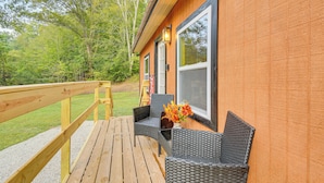 A wooden deck with wicker furniture and a vase of flowers. - Hudsons Hideaway Cabin on Creek in Beattyville! (Beattyville)