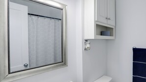 Een badkamer met een wit wastafel, een spiegel, een toilet en een handdoekhouder.