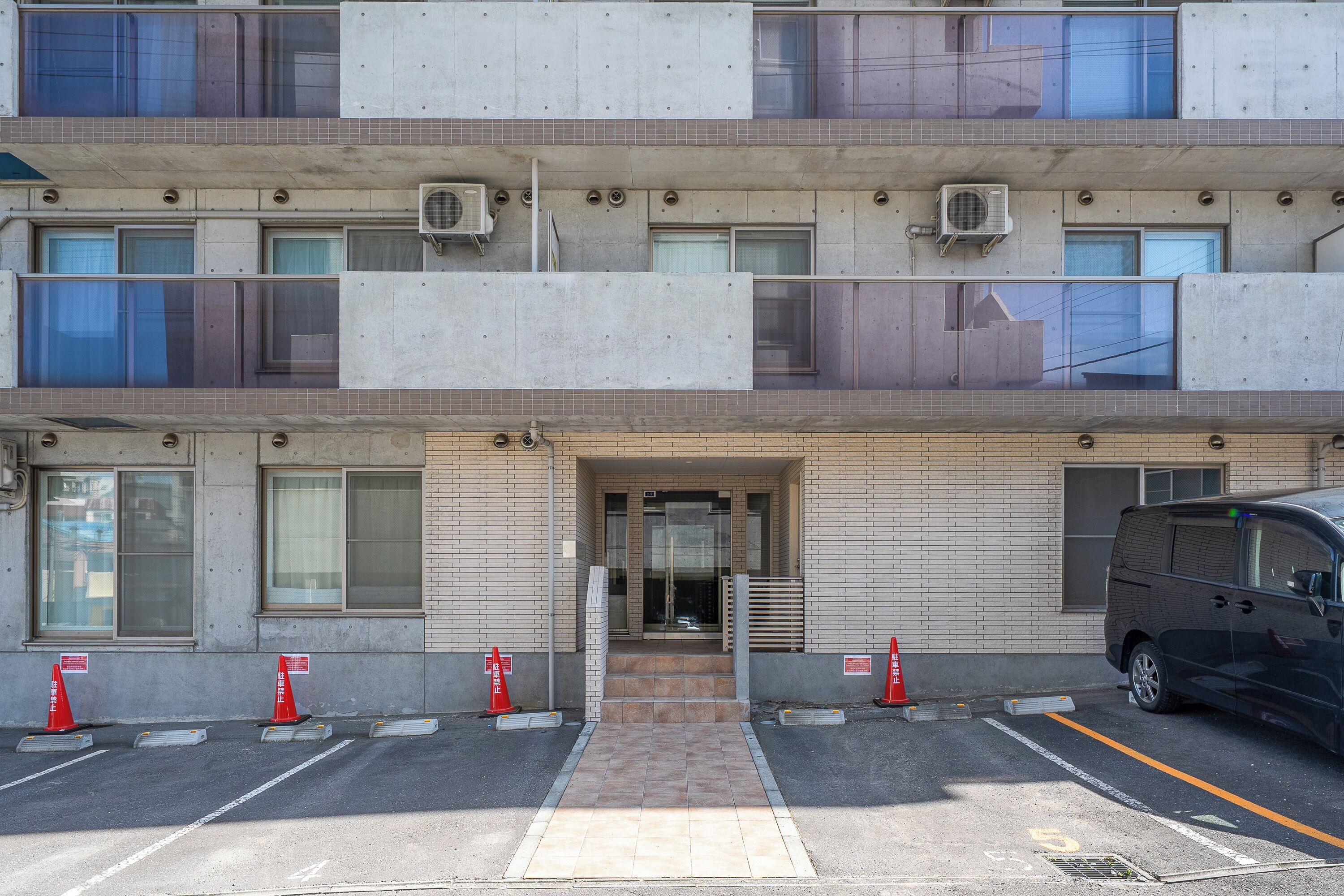 A multi-story building with a parking area in front.
