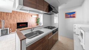A modern kitchen with wooden cabinets, a built-in stove, and a sink. - OTARU SAMPO 2 (Otaru)