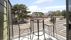 A balcony with a table and two chairs, overlooking a parking area and buildings. - The Biggest Little Downtown Escape (Reno)