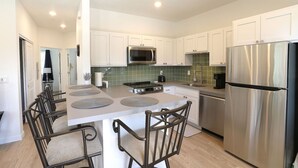 A modern kitchen with white cabinets, stainless steel appliances, and a central island with seating. - The Biggest Little Downtown Escape (Reno)
