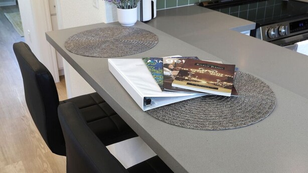 A kitchen with a modern design, featuring a countertop, a stove, and a dining area with a chair and a table. - Reno`s Downtown and Midtown Getaway (Reno)