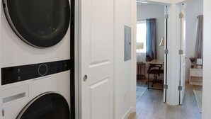 A hallway with a double-door laundry room, a dining area with a table and chairs, and a view into a living space. - Reno`s Downtown and Midtown Getaway (Reno)