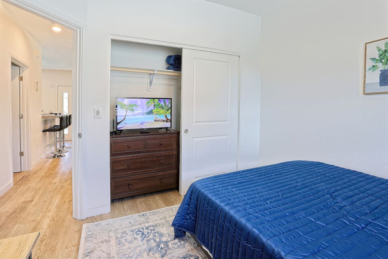 Een slaapkamer met een bed, een dressoir, een televisie en een zithoek met stoelen.