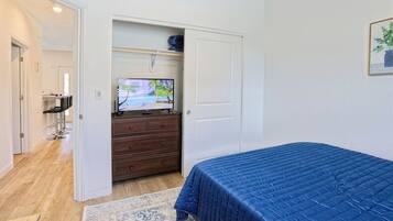 Een slaapkamer met een bed, een dressoir, een televisie en een zithoek met stoelen.