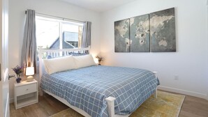 A bedroom with a bed, nightstands, a window with curtains, a world map artwork, and a yellow rug. - Reno`s Downtown and Midtown Getaway (Reno)