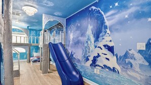 A room with a blue slide, a mural of a snowy mountain, and a chandelier. - Super Mario & Frozen Castle Ultimate Stay with Free Access to Resort by Disney (Kissimmee)