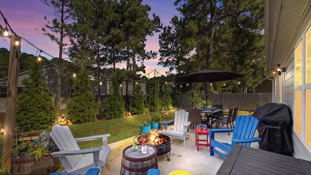 An outdoor patio with a fire pit, seating, and string lights. - Modern 3BR Home w/ Backyard, Firepit & Near DT (New Bern)