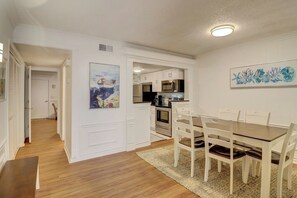 A modern kitchen with white cabinetry, a dining table with chairs, and artwork on the walls.