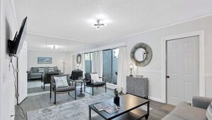 A modern living room with a sofa, armchairs, a coffee table, and a television mounted on the wall. - Central Hilton Head Retreat 2BR Near Beaches (Hilton Head Island)