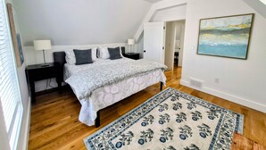 Ein Schlafzimmer mit einem Bett, Nachttischen, einem Gemälde und einem gemusterten Teppich.