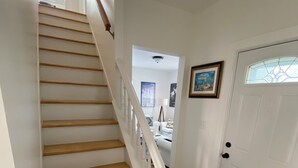 Eine Treppe mit Holzstufen und weißen Geländern, die zu einer Tür mit Glasfenster führt.