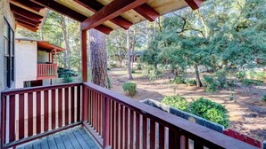 A covered porch with a wooden railing, overlooking a landscaped garden with trees and shrubs. - Hilton Head 2BR Escape w/ Pool & Sofa Bed (Hilton Head Island)