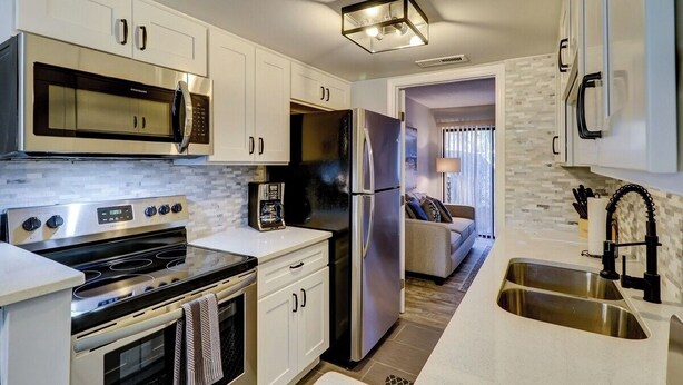 A modern kitchen with white cabinets, stainless steel appliances, and a built-in oven. - Hilton Head 2BR Escape w/ Pool & Sofa Bed (Hilton Head Island)