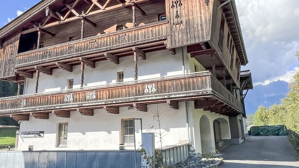 Ein traditionelles Holzgebäude mit Balkonen und einem Schild, auf dem "EINFÄHRT TIEFGARBE" steht.