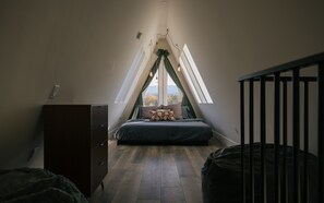 A bedroom with a sloped ceiling, a bed with pillows, a dresser, and a view through a window. - Stowe A-Frame, Sauna, Hot Tub, Theater, Game Room, Arcade, Gym (Morristown)