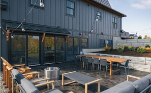 An outdoor patio with a wooden table and chairs, a metal grill, and string lights. - Stowe A-Frame, Sauna, Hot Tub, Theater, Game Room, Arcade, Gym (Morristown)