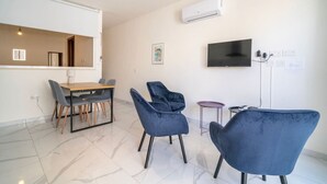 Ένα σύγχρονο σαλόνι με τραπεζαρία, τηλεόραση επίπεδης οθόνης και κλιματιστικό.