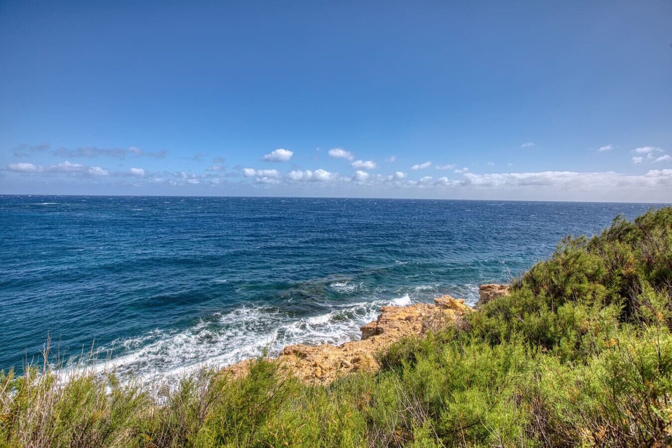 A coastal landscape with rocky terrain and dense greenery.
