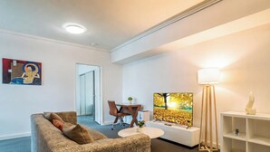 Un salon avec un canapé, un téléviseur, une lampe et un tableau au mur.