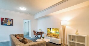 Una sala de estar con un sofá, un televisor, una lámpara y un cuadro en la pared.