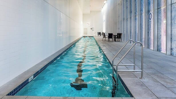 Une piscine intérieure à l’eau claire, dotée d’un plongeoir et d’un sol carrelé.