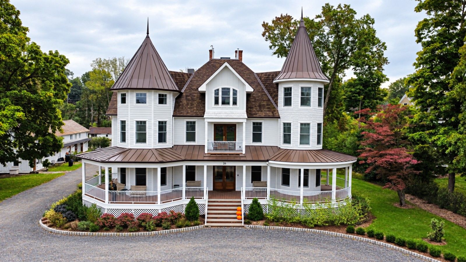 A large, two-story house with a wrap-around porch and two towers.