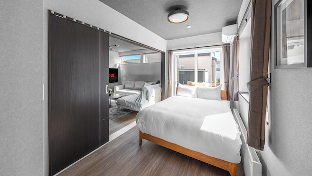 Una habitación de hotel moderna con cama, sofá, televisión y puerta corredera.