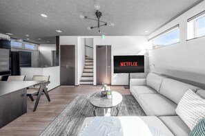 Una sala de estar moderna con un sofá, una mesa de centro y un televisor mostrando 'NETFLIX'.