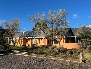 Une maison à deux étages avec un porche, entourée d’arbres et bordée d’une allée en gravier.