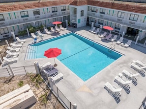 Et hotel med swimmingpool omgivet af liggestole og parasoller.